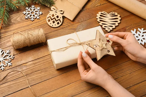 木製の背景にクリスマスの贈り物を作る女性 クローズアップ — ストック写真