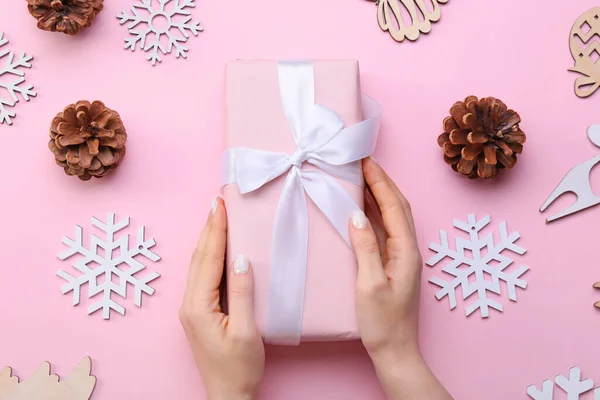 Weibliche Hände Mit Weihnachtsgeschenk Und Dekorationen Auf Rosa Hintergrund Nahaufnahme — Stockfoto