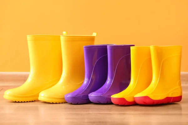Many different rubber boots near color wall