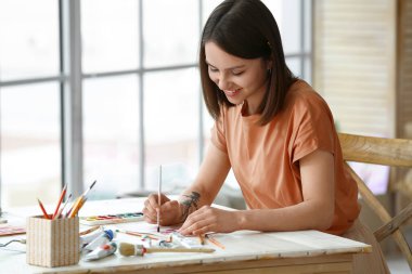 Atölyede resim yapan genç bir kadın sanatçı