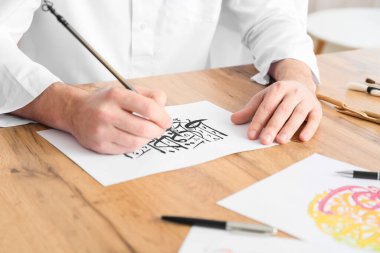 Erkek Arap kaligrafçı ofiste çalışıyor, yakın plan.