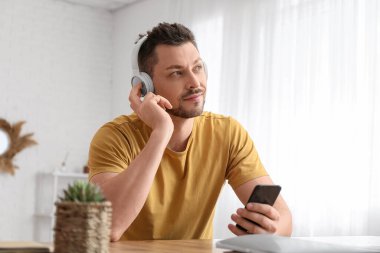Masada telefon ve kulaklıklı bir adam var.