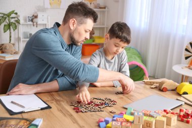 Ofiste küçük bir çocukla çalışan erkek psikolog. Otizm kavramı