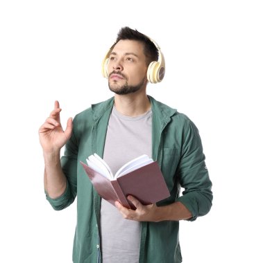 Kulaklık takan ve beyaz arka plan üzerine kitap yazan bir adam.