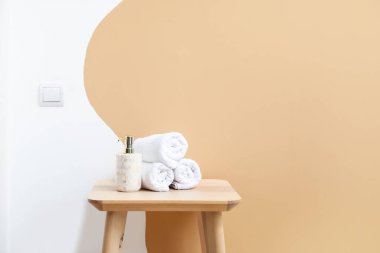 Renkli duvarın yanında havluları ve kozmetik şişesi olan masa.