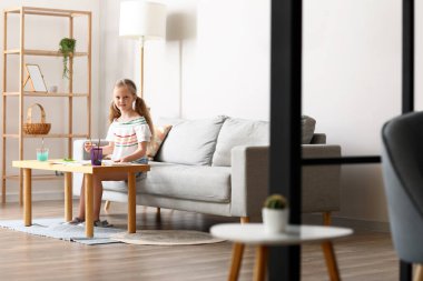 Masada suluboya resim yapan küçük bir kız.