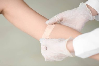 Hemşire klinikte kadının koluna sıva uyguluyor.