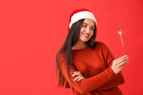 若いです女性とともにクリスマススパークラー上の赤い背景 — ストック写真