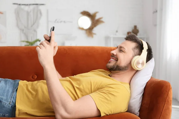 Man Med Telefon Och Hörlurar Liggande Soffan — Stockfoto