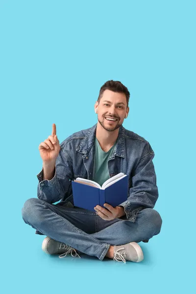 Homem Com Fones Ouvido Livro Apontando Para Algo Fundo Cor — Fotografia de Stock