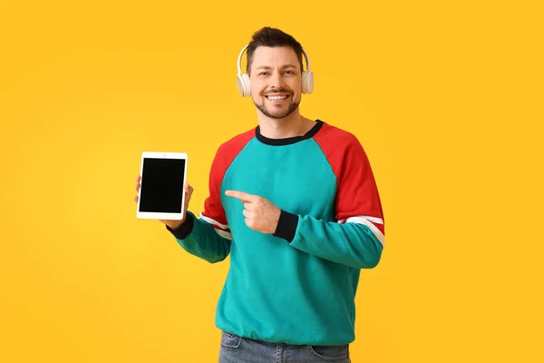 タブレットコンピュータとヘッドフォンを持つ男の色の背景 — ストック写真