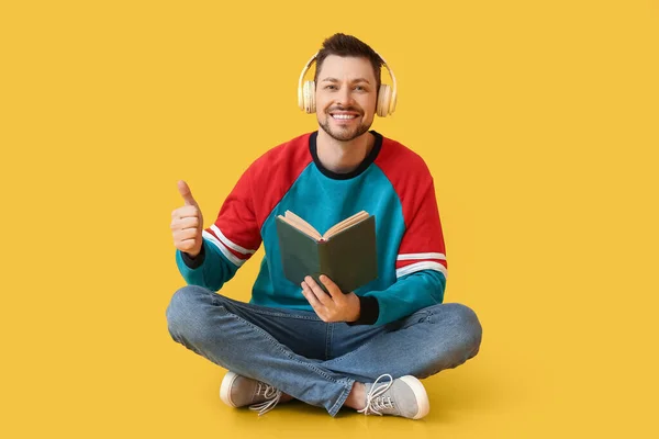 Pria Dengan Headphone Dan Buku Menampilkan Thumb Pada Latar Belakang — Stok Foto