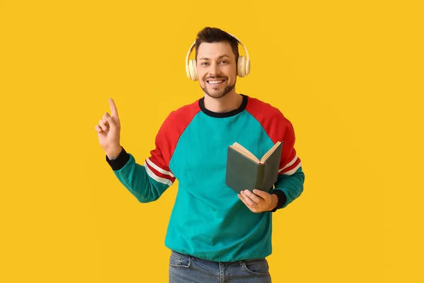 Man Headphones Book Pointing Something Color Background — Stock Photo, Image