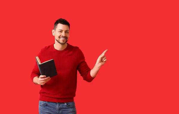 Man Met Oortjes Boek Wijzend Naar Iets Kleur Achtergrond — Stockfoto