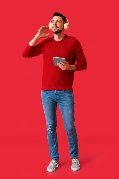 タブレットコンピュータとヘッドフォンを持つ男の色の背景 — ストック写真