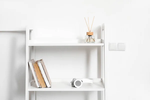 Plankkast Met Koptelefoon Boeken Rietstrooier Bij Witte Wand — Stockfoto