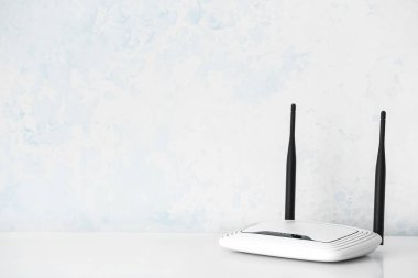Beyaz duvarın yanındaki masada modern wi-fi yönlendirici