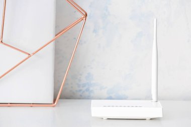 Işık duvarının yanındaki masada modern Wi-Fi yönlendirici ve dekor ögesi