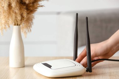 Kadın masadaki kablosuz internet yönlendiricisine ethernet kablosu yerleştiriyor.