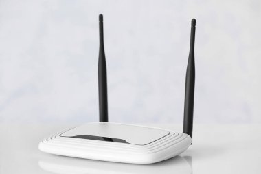 Beyaz duvarın yanındaki masada modern wi-fi yönlendirici