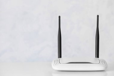 Beyaz duvarın yanındaki masada modern wi-fi yönlendirici