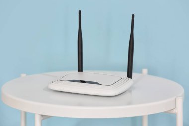 Modern Wi-Fi yönlendirici mavi duvarın yanındaki masada.