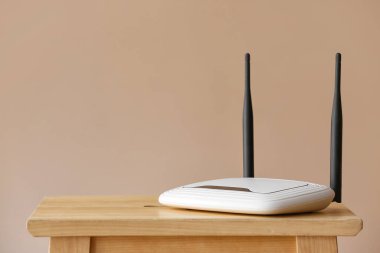 Bej duvarın yanındaki masada modern wi-fi yönlendirici