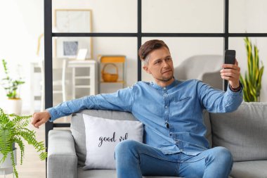 Yakışıklı adam evde selfie çekiyor.