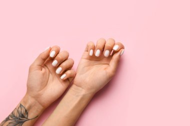 Pembe arka planda moda manikürlü bir kadın.