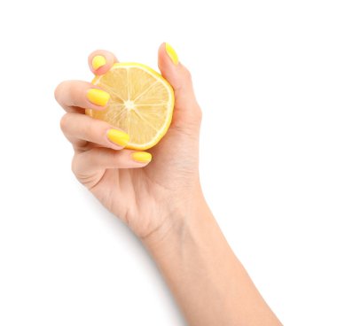 Güzel manikürlü genç bir kadın beyaz arka planda dilimlenmiş limon tutuyor.