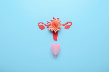 Renkli arkaplanda regl fincanı ve çiçekli kompozisyon