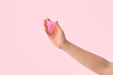 Pembe arka planda regl bardağı olan bir kadın.