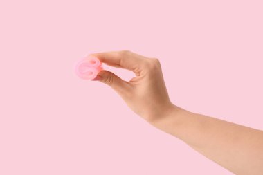 Pembe arka planda regl bardağı olan bir kadın.