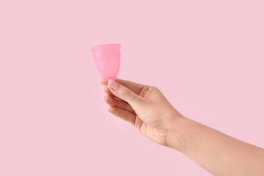 Pembe arka planda regl bardağı olan bir kadın.