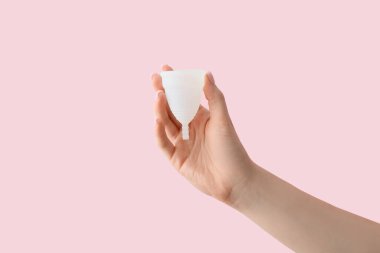 Pembe arka planda regl bardağı olan bir kadın.