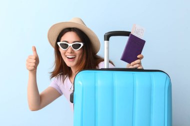Pasaportu ve bavulu renkli genç bir kadın.