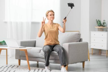 Oturma odasında selfie çeken genç bir kadın.