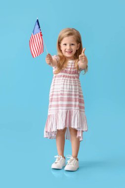 Mavi arka planda ABD bayrağı gösteren komik küçük kız.