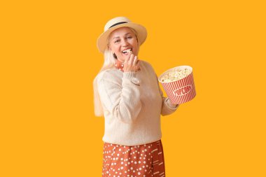 Olgun bir kadın arka planda lezzetli patlamış mısır yiyor.