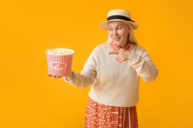 Olgun kadın arka planda lezzetli patlamış mısırı işaret ediyor