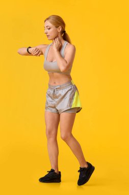 Kadın koşucu renk arkaplanındaki nabzı kontrol ediyor