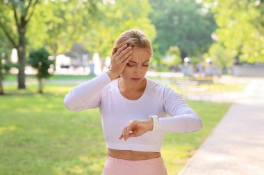 Kadın koşucu dışarıda nabzı kontrol ediyor.