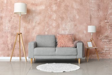 Rahat gri kanepe ve pembe duvarın yanındaki lambalar.