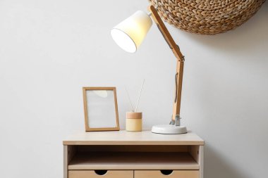 Sazlık dağıtıcı ile parlayan lamba ve ışık duvarının yanındaki masada boş çerçeve