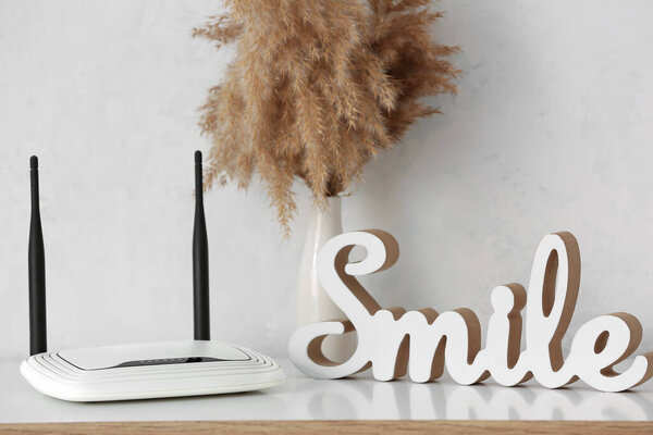 Современный Wi-Fi маршрутизатор и элемент декора на столе возле белой стены