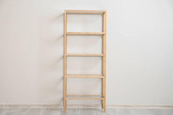 Stylish wooden shelf unit near light wall