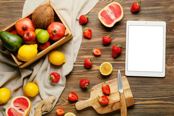 Digital recipe book and different fruits on wooden background
