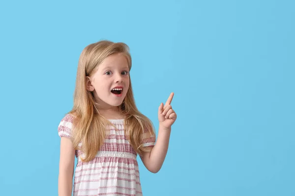 Şaşırmış Küçük Kız Mavi Arka Plandaki Bir Şeyi Işaret Ediyor — Stok fotoğraf
