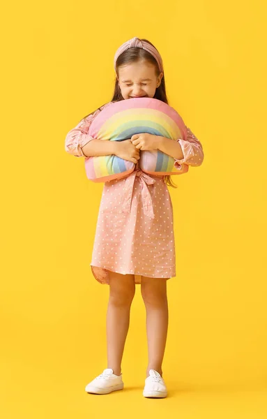 可爱的小女孩抱着黄色背景的玩具彩虹 — 图库照片