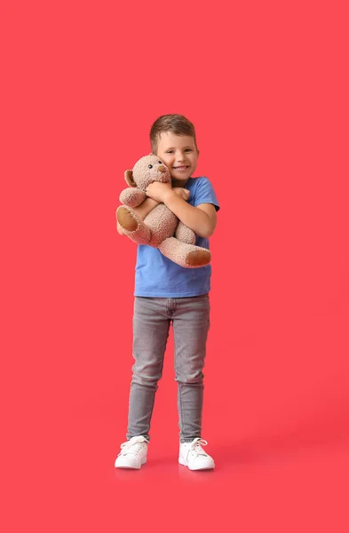 Netter Kleiner Junge Umarmt Teddybär Auf Rotem Hintergrund — Stockfoto